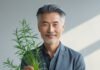 Can You Reverse Grey Hair Naturally? Smiling man with healthy grey hair holding fresh herbal roots, symbolizing natural remedies for reversing grey hair